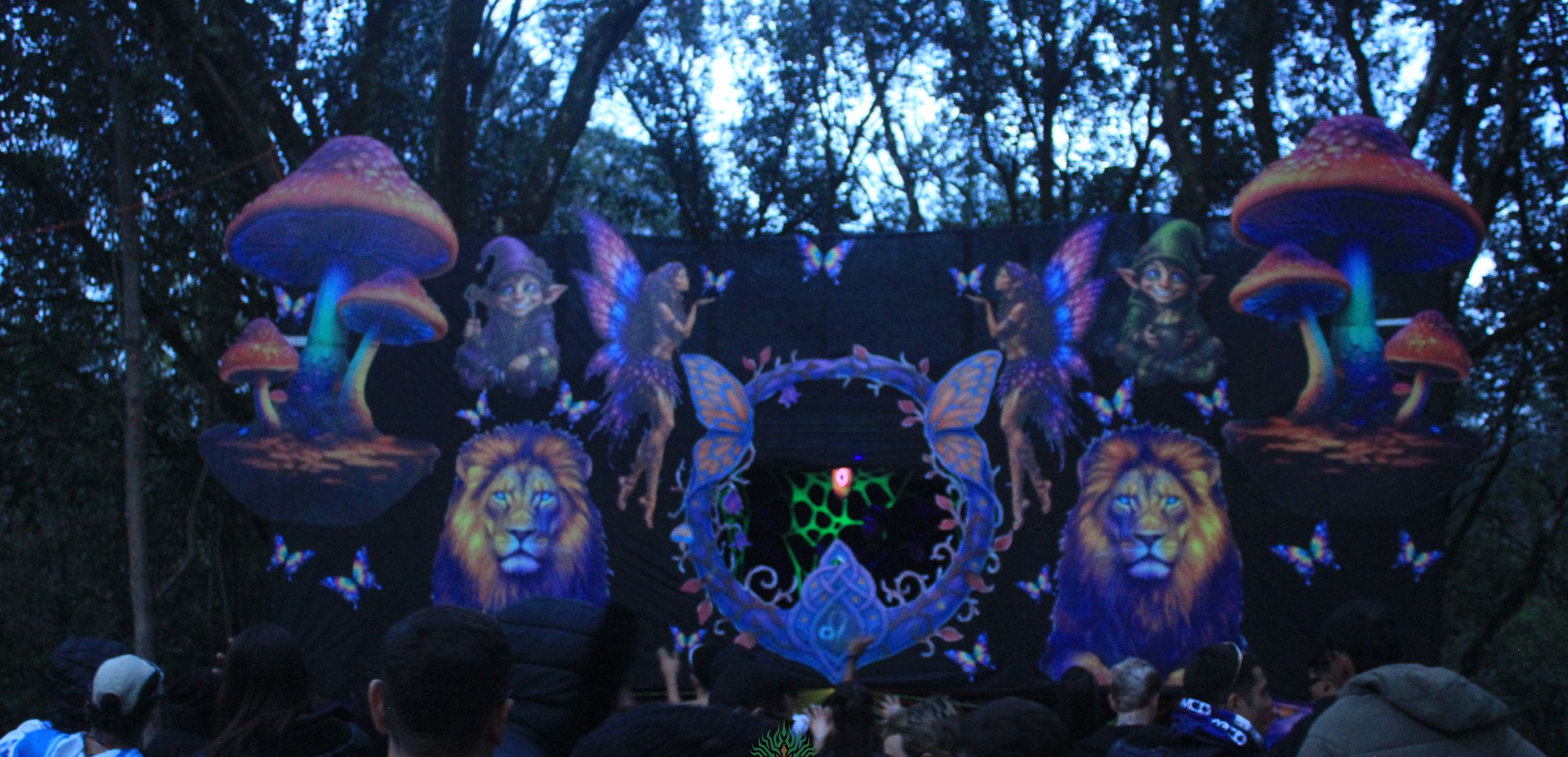 O palco da festa iluminado em luz negra, na mata